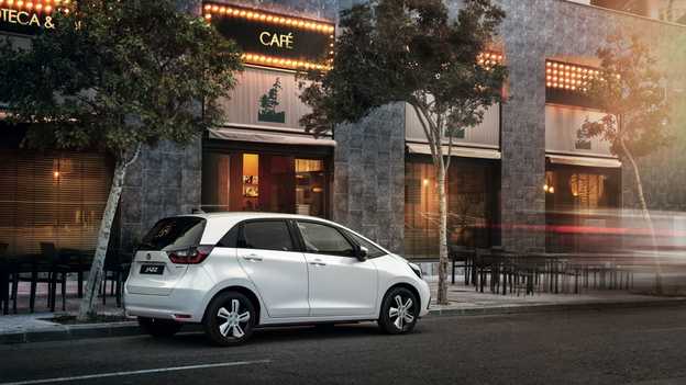 Honda Jazz Hybrid parkert utenfor en kafé, sett bakfra