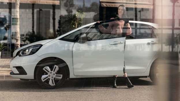 Parkert Honda Jazz sett fra siden parkert med dame som åpner døren