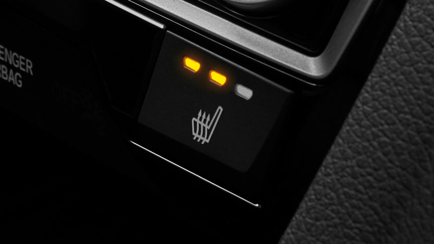 Nærbilde av knapp for oppvarmede bakseter i firedørs Honda Civic.