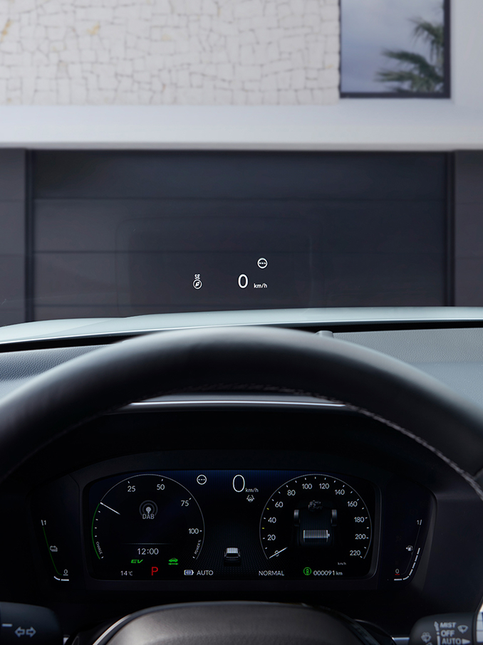 Et førstepersonsperspektiv fra førersetet som viser et head-up-display (HUD) som projiserer «50 km/t» og et kompass på frontruten over en grusvei.