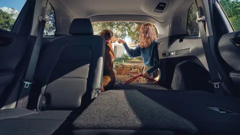 CR-V Plug in Hybrid SUV baksete tilbakelent med kvinne og hund ved det åpne bagasjerommet. 