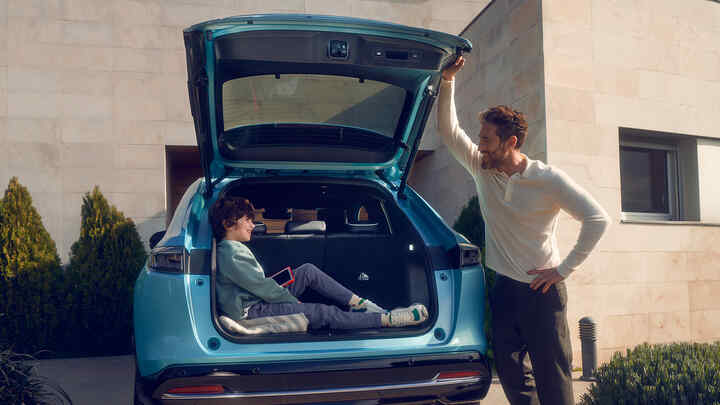 En far snakker til barnet sitt som sitter i bagasjeområdet på Honda e:Ny1.