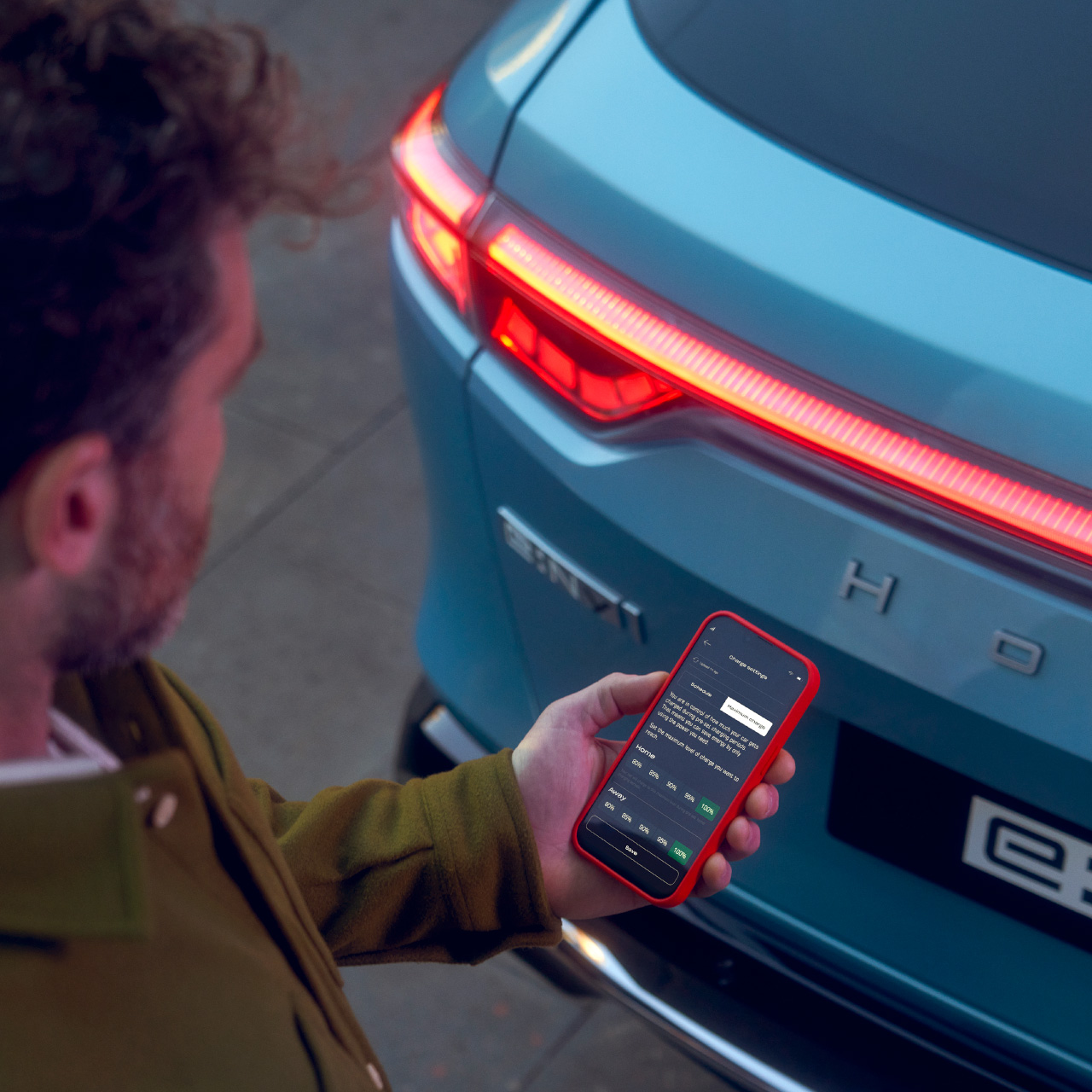 Mann ser på My Honda+-appen ved siden av Honda e:Ny1