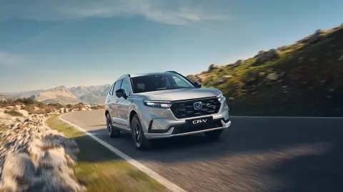 Hvit CR-V Plug-in Hybrid som kjører på veien i fjellet.