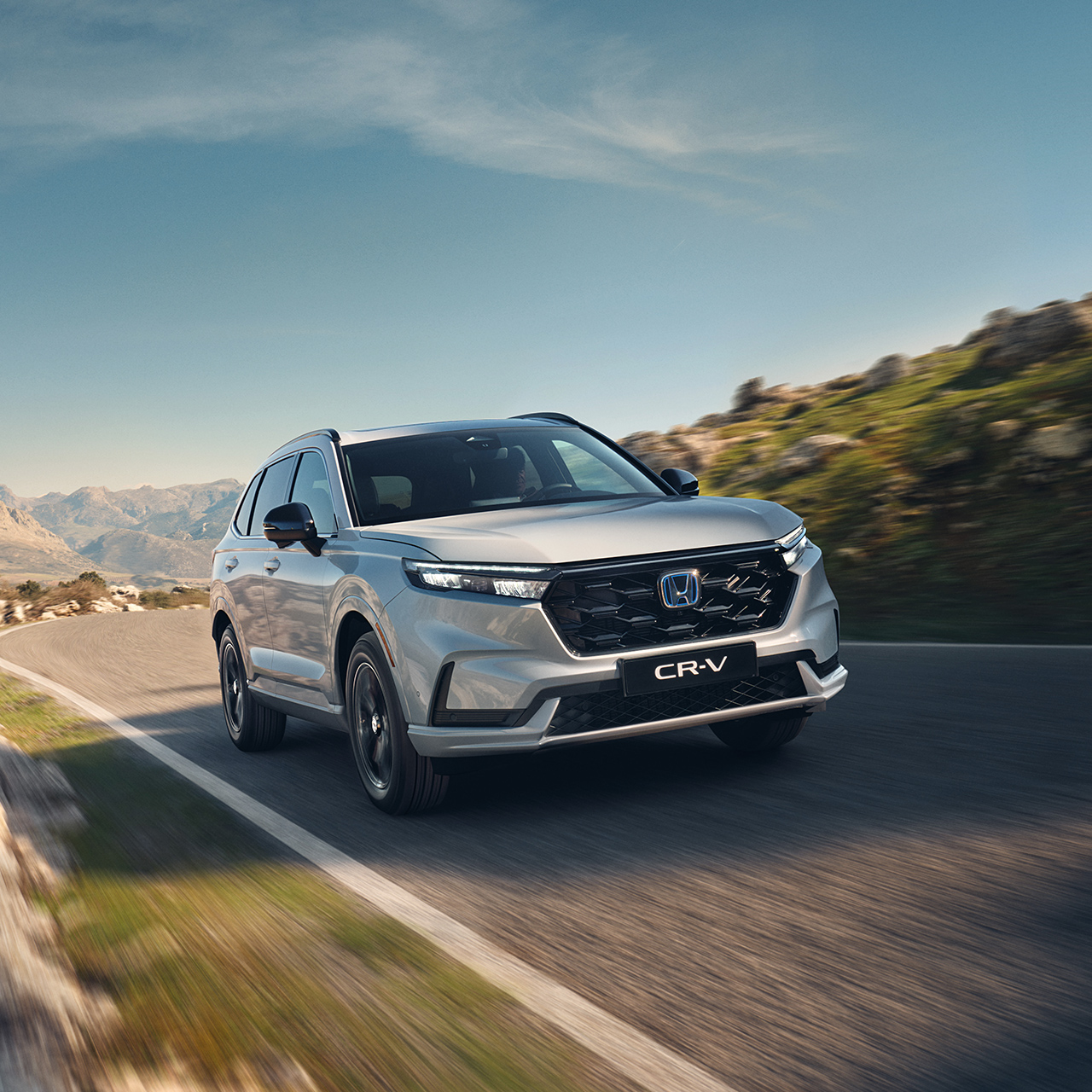 Hvit CR-V Plug-in Hybrid som kjører på veien i fjellet.