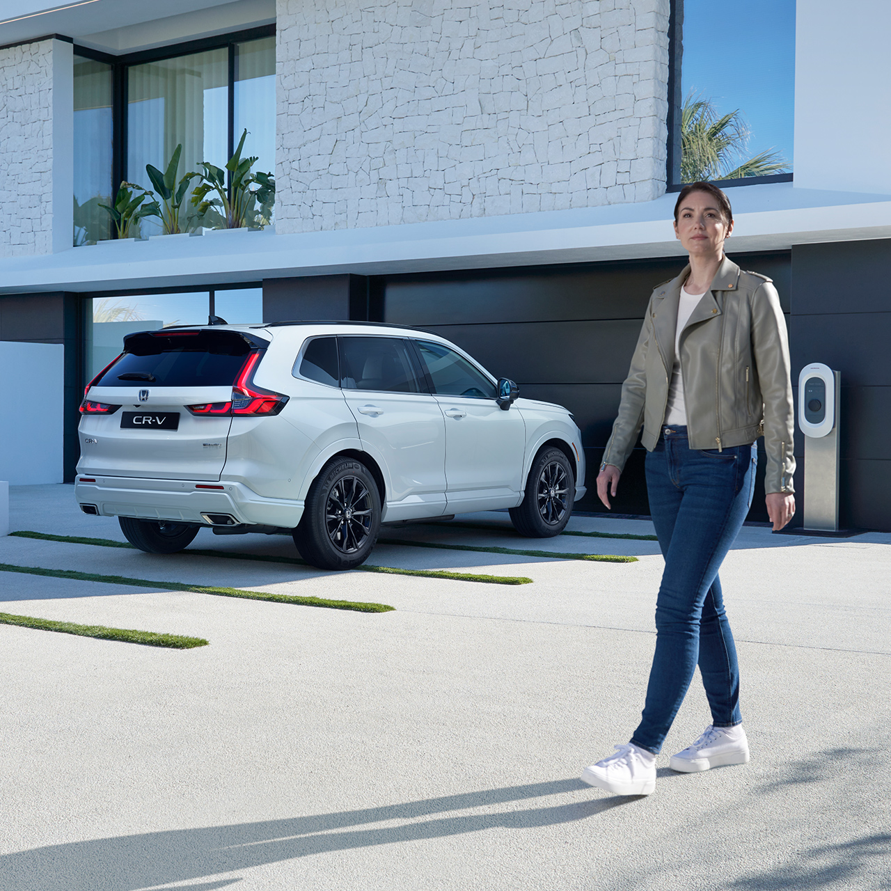 Modell som går i nærheten av parkert hvit CR-V Plug-in Hybrid-bil.