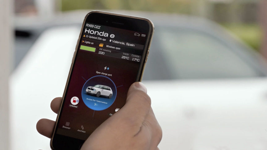 Mann som ser på My Honda+-appen med Honda Jazz Hybrid Crosstar i bakgrunnen. 