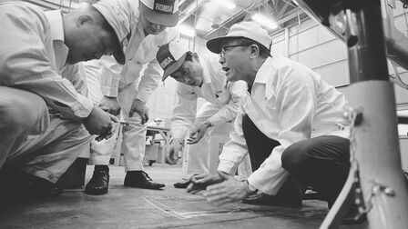 Soichiro Honda med fabrikkmedarbeidere i hvite kjeledresser.